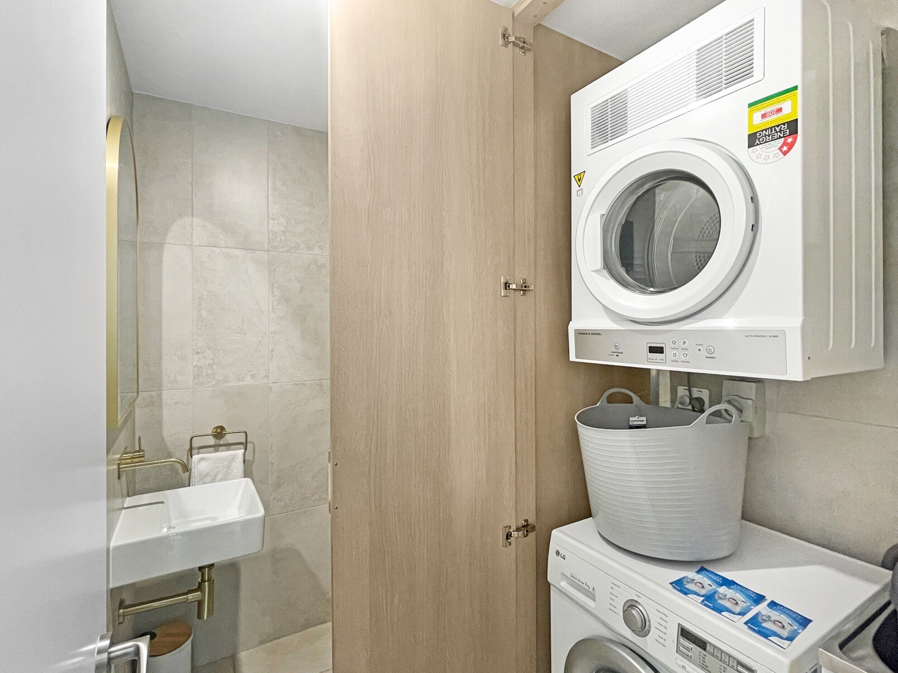 A compact laundry room with a front-loading washing machine, a dryer, and a sink.