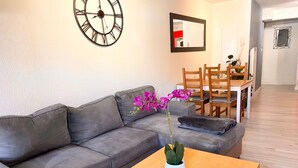 Un salon moderne avec un canapé gris, une table basse en bois et une orchidée en pot.