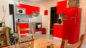 Une cuisine de taille réduite avec des meubles rouges, un four à micro-ondes et un réfrigérateur rouge.
