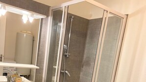 Une salle de bain moderne avec une douche à parois de verre, un lavabo avec des articles de toilette et un porte-serviettes.
