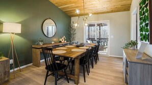 Comedor con mesa de madera, sillas negras y lámpara colgante.