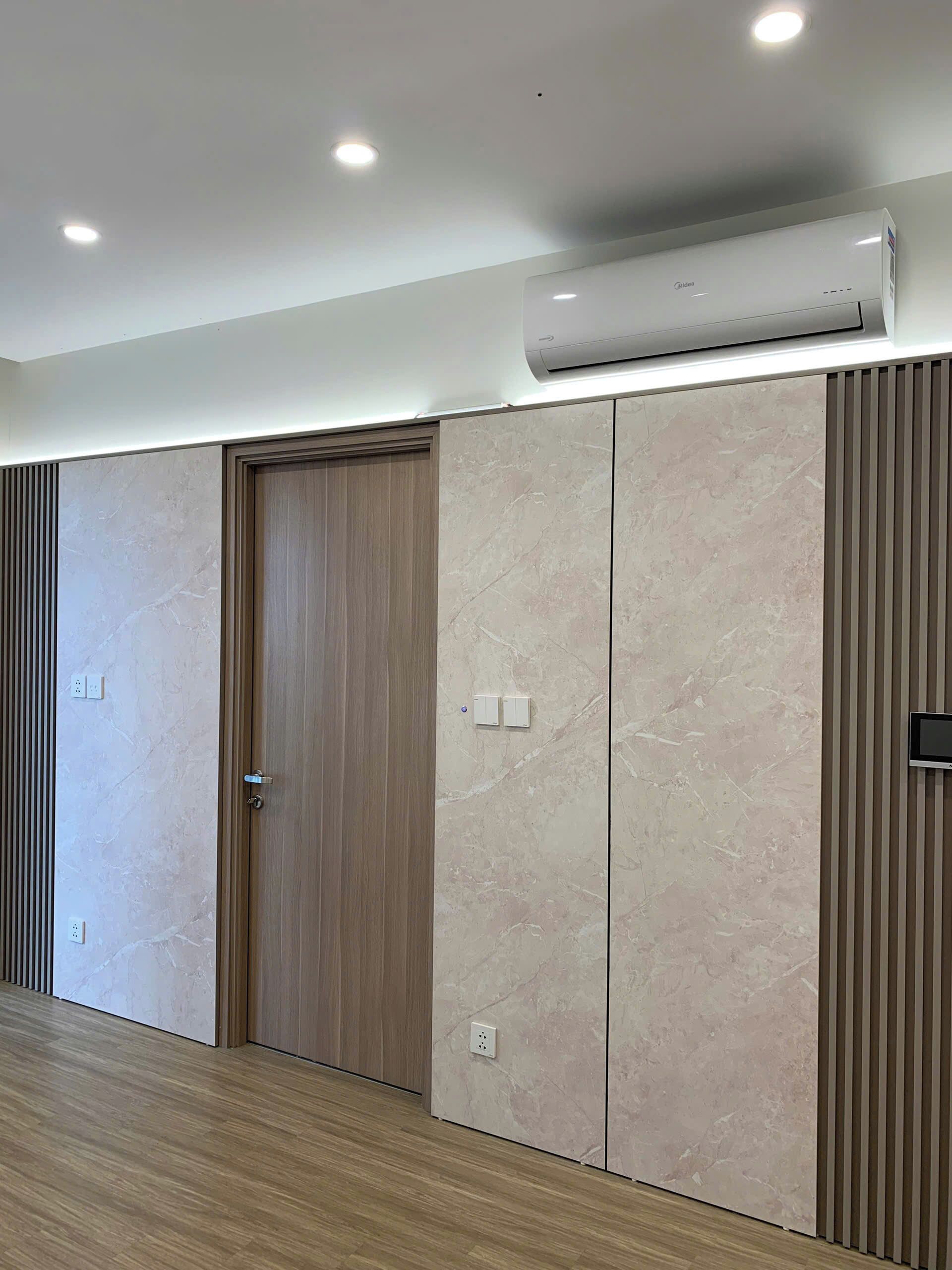A modern room with a wooden door, a large wardrobe, and an air conditioning unit on the ceiling.