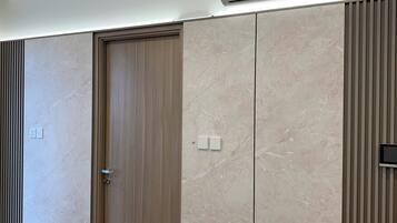 A modern room with a wooden door, a large wardrobe, and an air conditioning unit on the ceiling.