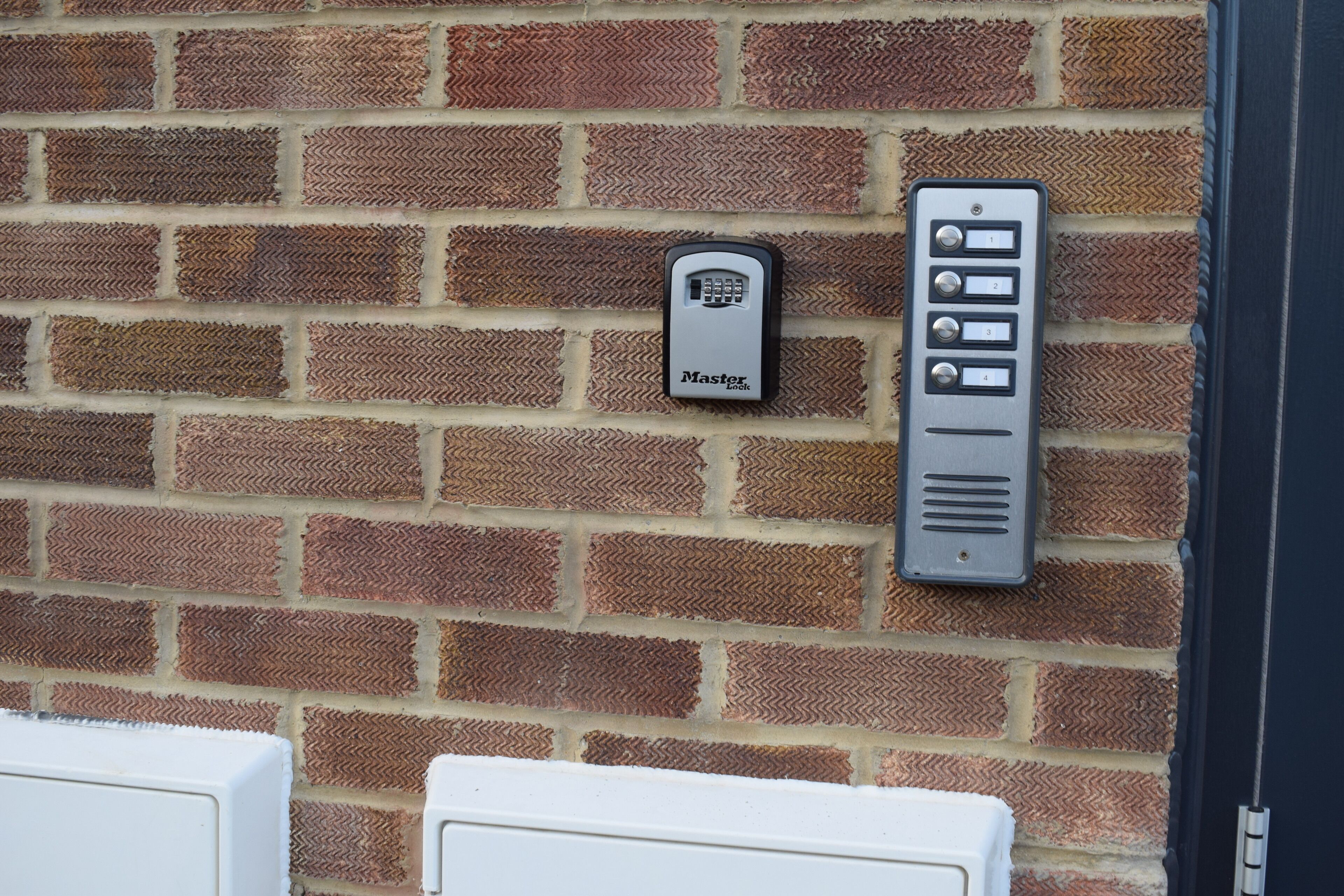 A brick wall with a doorbell and a keypad lock.