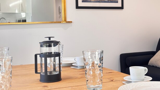 Een moderne keuken met een koffiezetapparaat, een grote spiegel en een lijst met een stadsgezicht aan de muur.