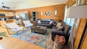 Ein gemütliches Wohnzimmer mit einer Couch, einem Sessel, einem Couchtisch und einem gemusterten Teppich.