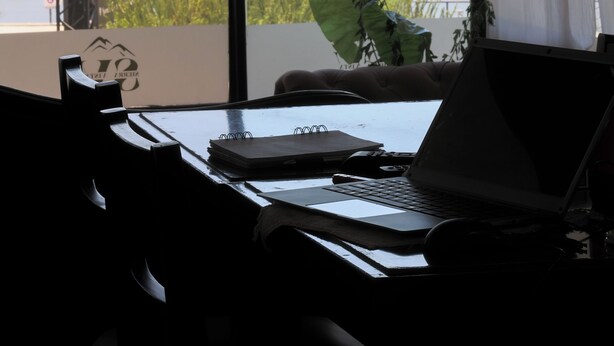 Una habitación con un ventanal grande con vistas a un pueblo, un escritorio con una computadora portátil y una planta.