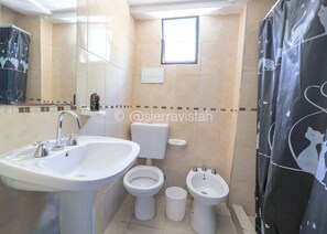 Une salle de bain équipée d’un lavabo, de deux toilettes, d’un bidet et d’un rideau de douche.