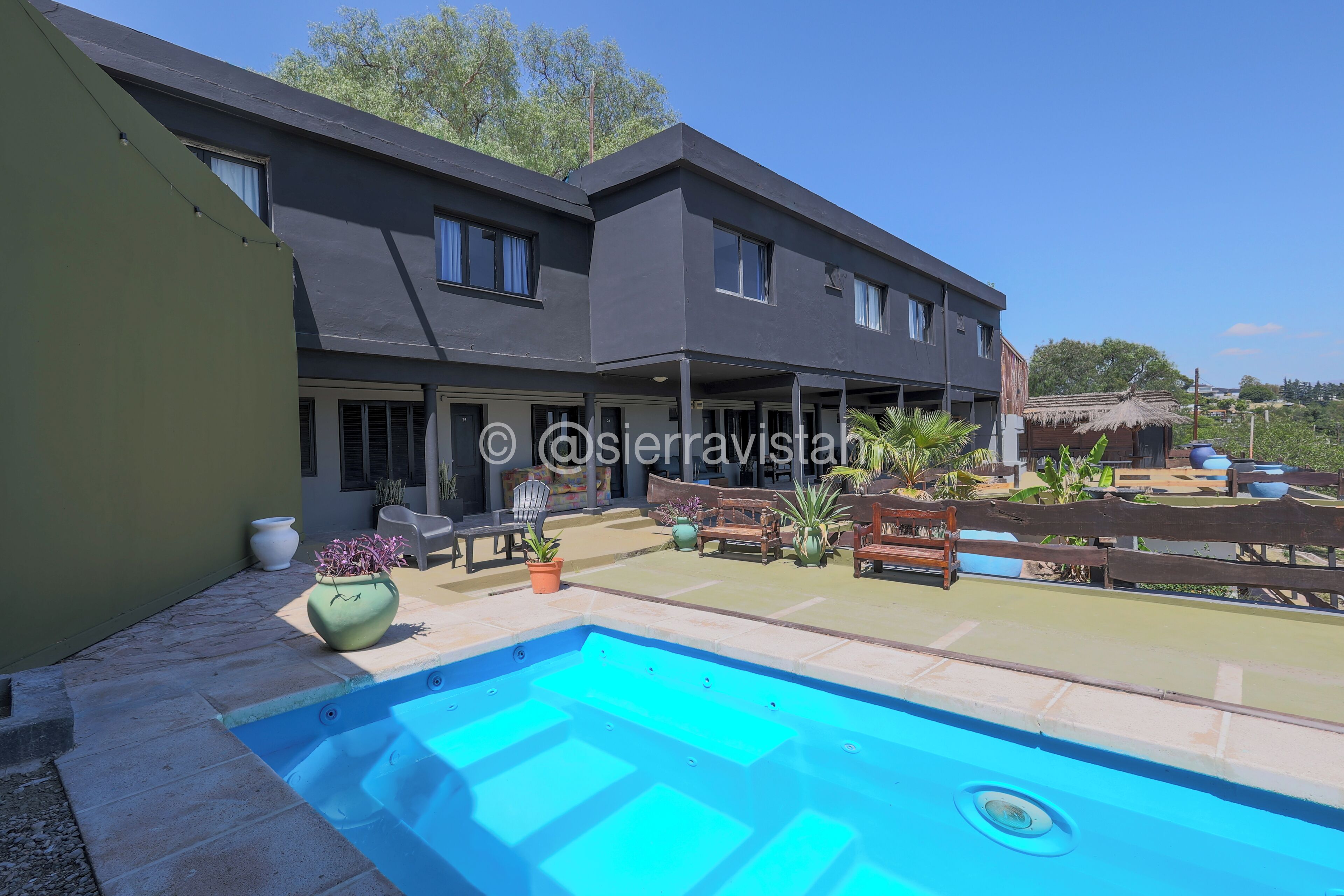 Una casa moderna de dos plantas con piscina, mobiliario exterior y patio trasero cercado.