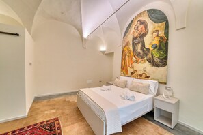A bedroom with a large bed, a nightstand, a wall-mounted painting, and a red carpet. - Incredible loft in the heart of Parma—a one-of-a-kind experience! (Parma)