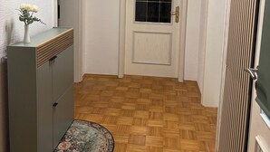 A hallway with a wooden floor, a coffee bar sign, a bathroom sign, and a door with a window.