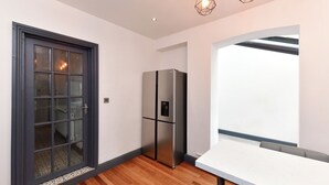 Eine moderne Küche mit großem Fenster, einem eingebauten Kühlschrank und Holzboden.