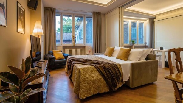 Una habitació d'hotel amb un llit gran, un escriptori, una cadira i una finestra amb cortines.