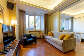 A living room with a sofa, a chair, a TV, and a table. - CAVOUR SUITE LUXURY 7, located in Galleria Cavour, Bologna's historic center. (Bologna)