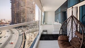 Een balkon met een hangstoel, uitzicht op een bouwplaats en een trap.