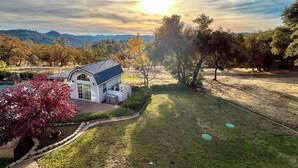 A house with a blue roof, surrounded by a well-maintained lawn and trees. - 'Whispering Oaks Estate' w/ Pool & View in Murphys (Murphys)