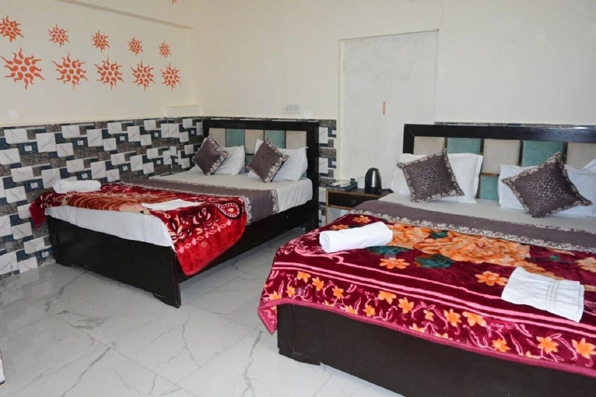 Duas camas de casal com colchas floridas, piso de azulejos e parede estampada.