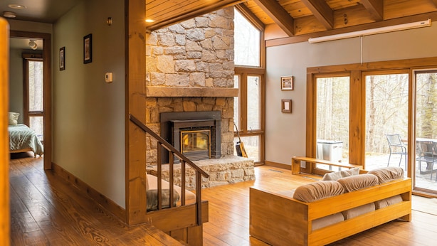 A spacious living area with a stone fireplace, wooden flooring, and a cozy seating area. - Joia Verde: Mtn Chalet -120 Acres -Adventure Ski Hike MTB Rafting (Charlemont)
