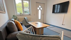Un salon moderne avec un canapé, une table à manger et un téléviseur fixé au mur.