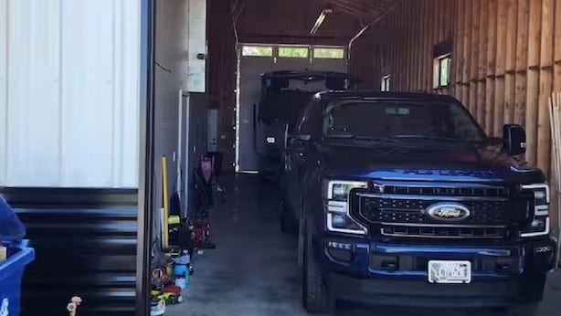 Ett fordon står inne i ett garage med träpanel på väggarna och ett betonggolv.