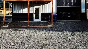 En tvåvåningsbyggnad med en balkong, ett garage och en grusuppfart.