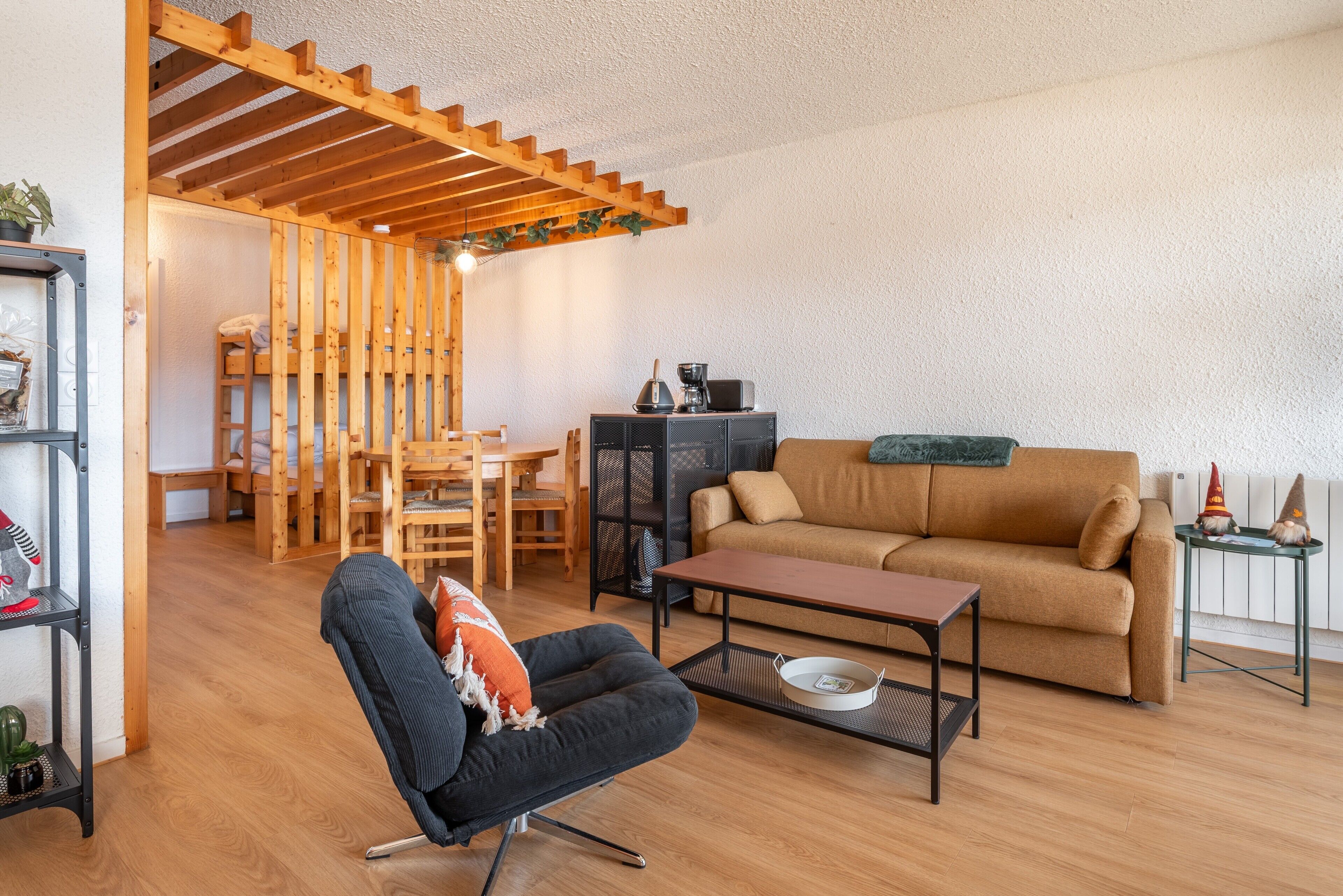 Un salon comprenant un canapé, une table basse, un fauteuil, une table à manger et une structure de plafond en bois.