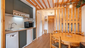 Une cuisine avec des poutres en bois, un four à micro-ondes et une table à manger avec des chaises.
