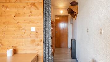 Un intérieur en bois agrémenté d’un rideau à motifs, d’une porte et d’une étagère fixée au mur.