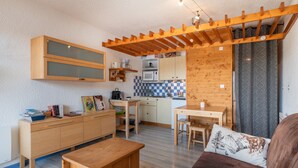 Un espacio habitable compacto con kitchenette, muebles de madera y una zona de estar acogedora.