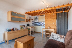 A compact living space with a kitchenette, wooden furniture, and a cozy seating area. - “Metamorphosis at the Summit” Apartment with Mountain View and Balcony (Villard-de-Lans)