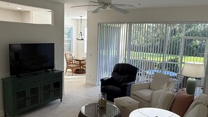 Ein Wohnzimmer mit Fernseher, Sofa, Couchtisch und Deckenventilator.