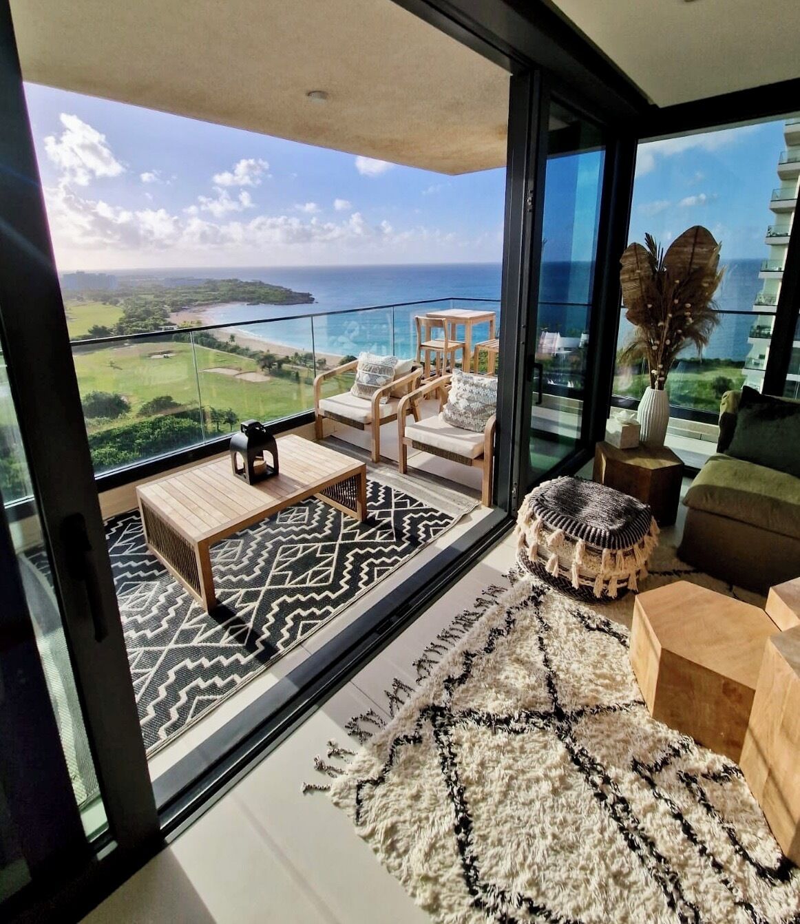 Un salon moderne doté d’une grande porte vitrée donnant sur un balcon avec vue sur un terrain de golf et l’océan.