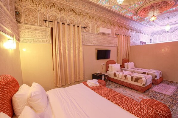 A room with two beds, a flat-screen TV, and ornate ceiling designs. - EMERALD PALACE (Marrakech)