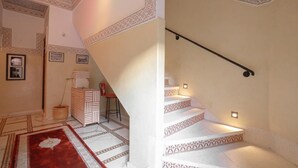 A staircase with patterned steps and a handrail, leading to a landing with a small table and a chair. - EMERALD PALACE (Marrakech)