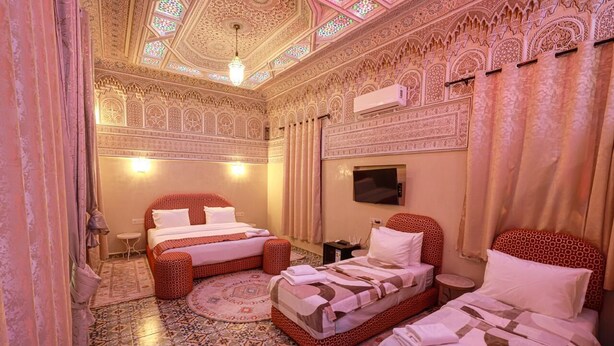 A room with two beds, a TV, and intricate ceiling and wall designs. - EMERALD PALACE (Marrakech)