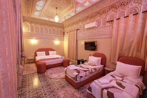 A room with two beds, a TV, and intricate ceiling and wall designs. - EMERALD PALACE (Marrakech)