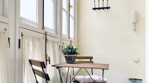 Une pièce avec une table en bois et deux chaises, une plante en pot et une poubelle.