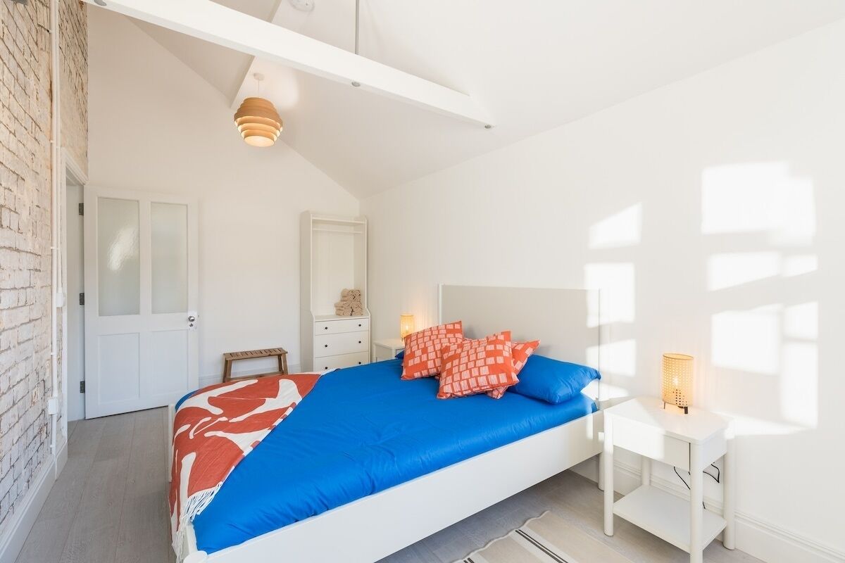 Une chambre à coucher avec un lit, des tables de chevet, une commode et une porte.