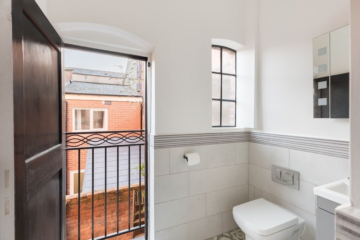 A bathroom with a toilet, a small window, and a mirror.