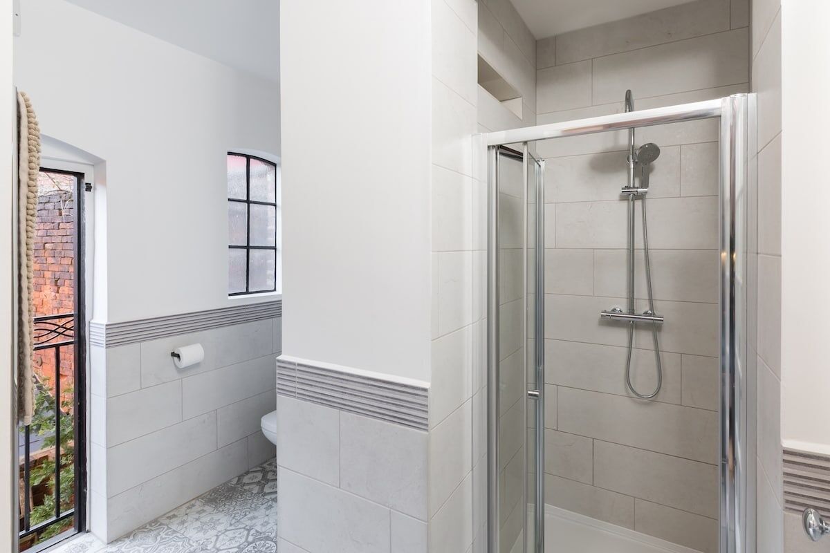 Une salle de bain avec une douche, des toilettes et une fenêtre.
