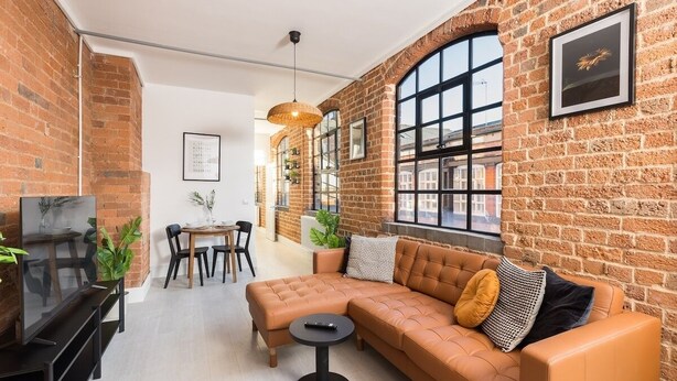 Un salon confortable avec un canapé en cuir, un téléviseur et un coin repas comprenant une table et des chaises.