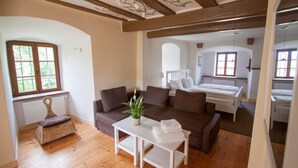 A cozy room with a wooden floor, a white table with a plant, a brown sofa, and a bed with white bedding. - Hohenhardt Castle - entire castle exclusive (Wiesloch)