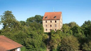 A stone building with a red-tiled roof, surrounded by dense greenery. - Hohenhardt Castle - entire castle exclusive (Wiesloch)