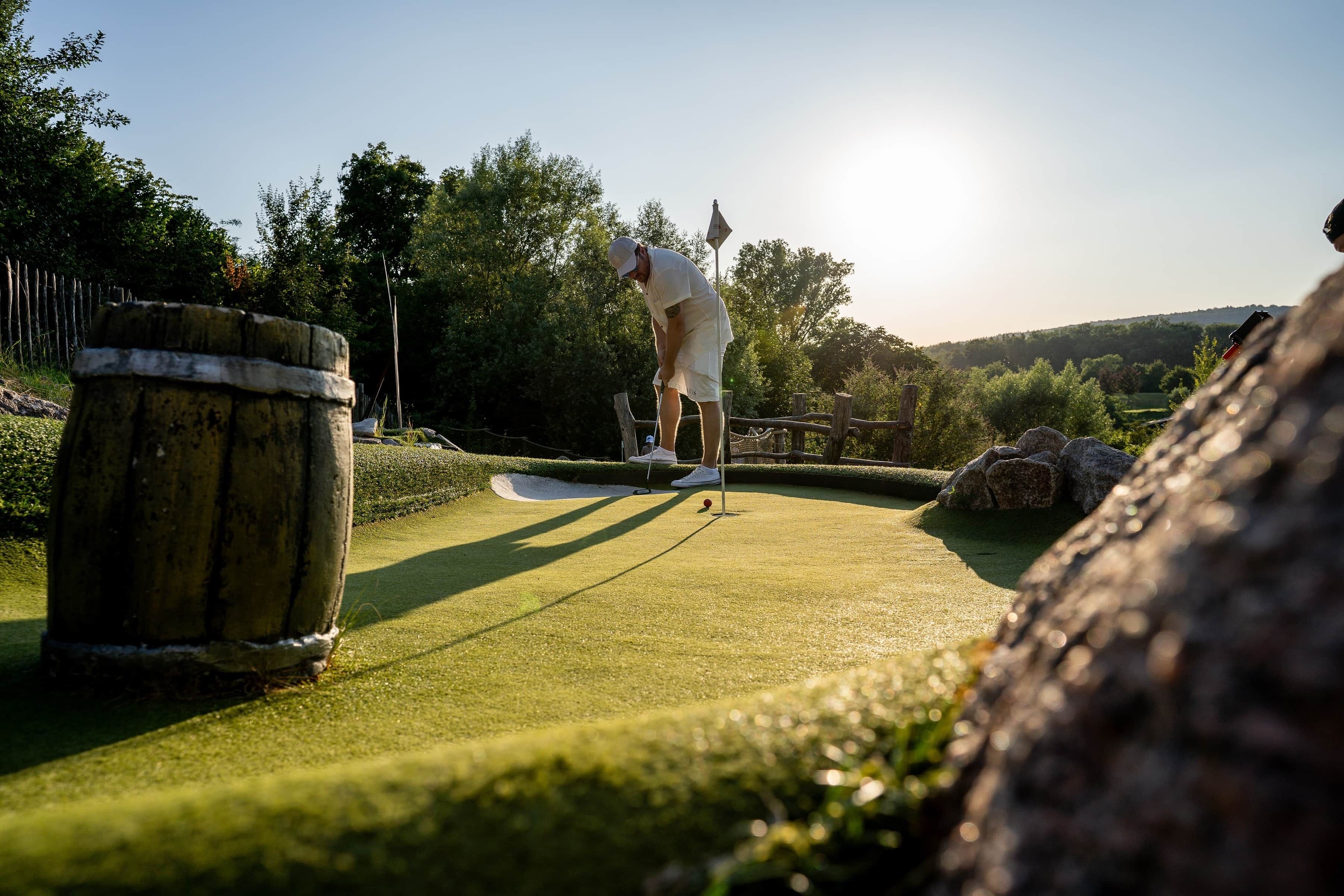 Een persoon speelt golf op een golfbaan, met een houten paal en een vlag.