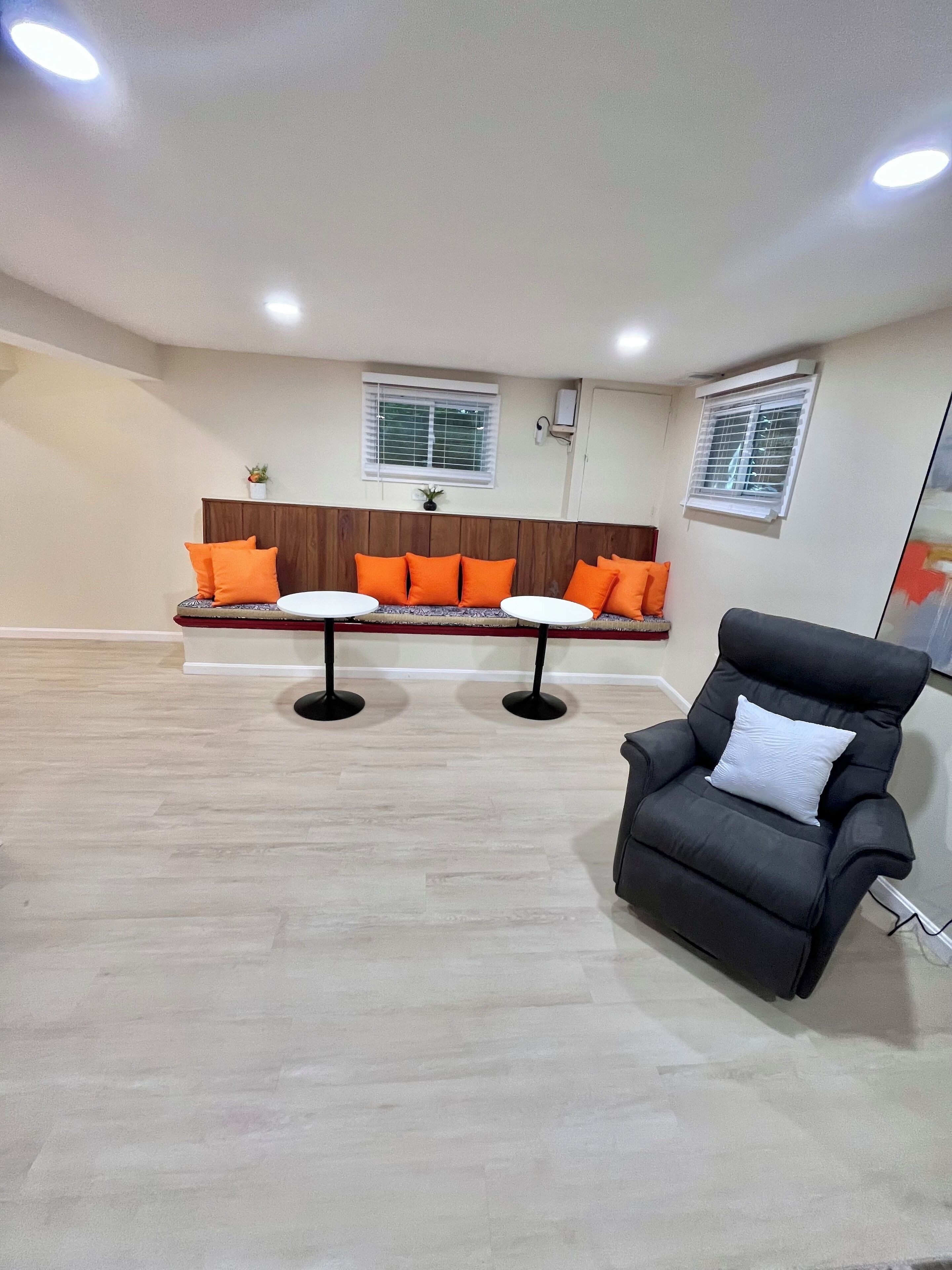 Een moderne woonkamer met een gebogen bank, twee ronde tafels en een zwarte fauteuil.