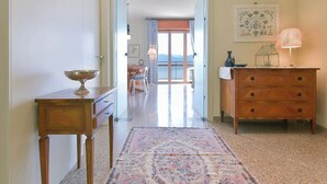 Corredor que leva a uma sala de jantar com vista para montanhas, um aparador de madeira e uma mesa com abajur.