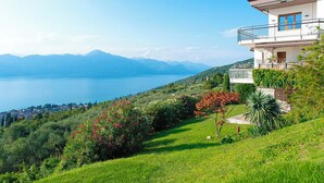Uma casa moderna de dois andares com varanda e vista para um lago e montanhas.