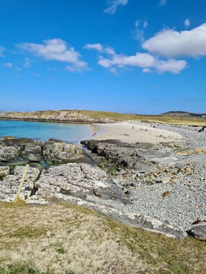 A rocky beach with clear blue water and a sandy shore.