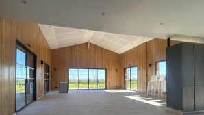 A spacious interior with wooden walls, large windows, and a tiled floor.