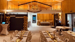 A spacious hall with a high ceiling, a central stage, and a long dining table set for a banquet.